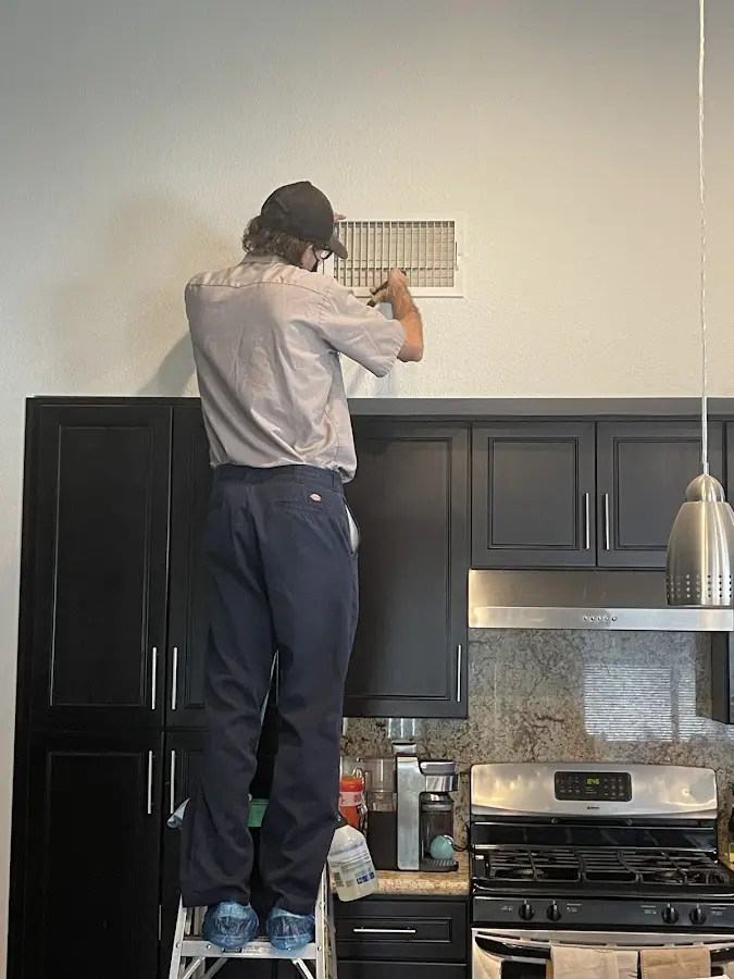 Technician inspecting an air vent during HVAC service in Meadowbrook
